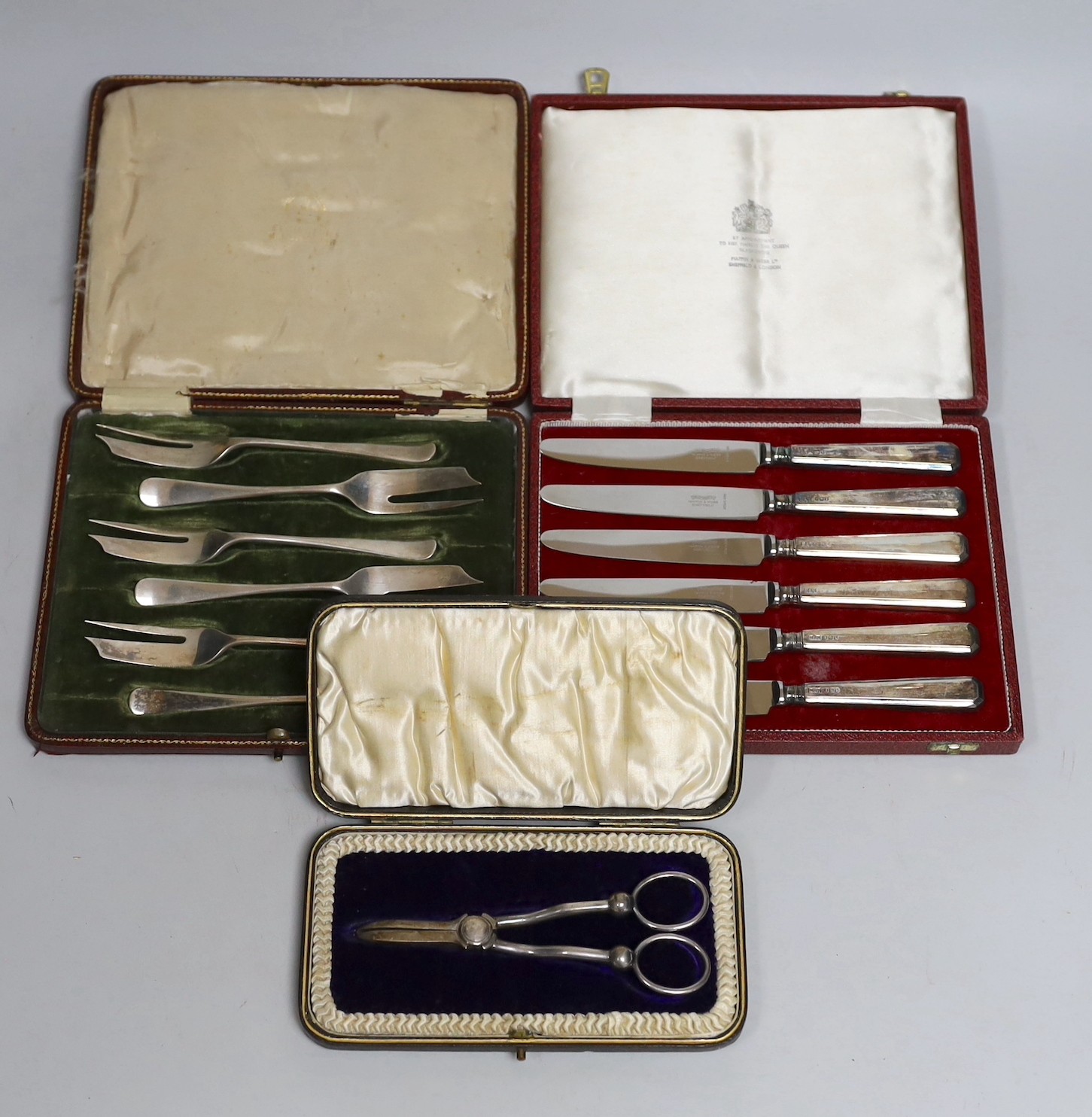 A cased set of Edwardian silver grape shears, Sheffield, 1901 and two other cased sets including cake forks and tea knives.